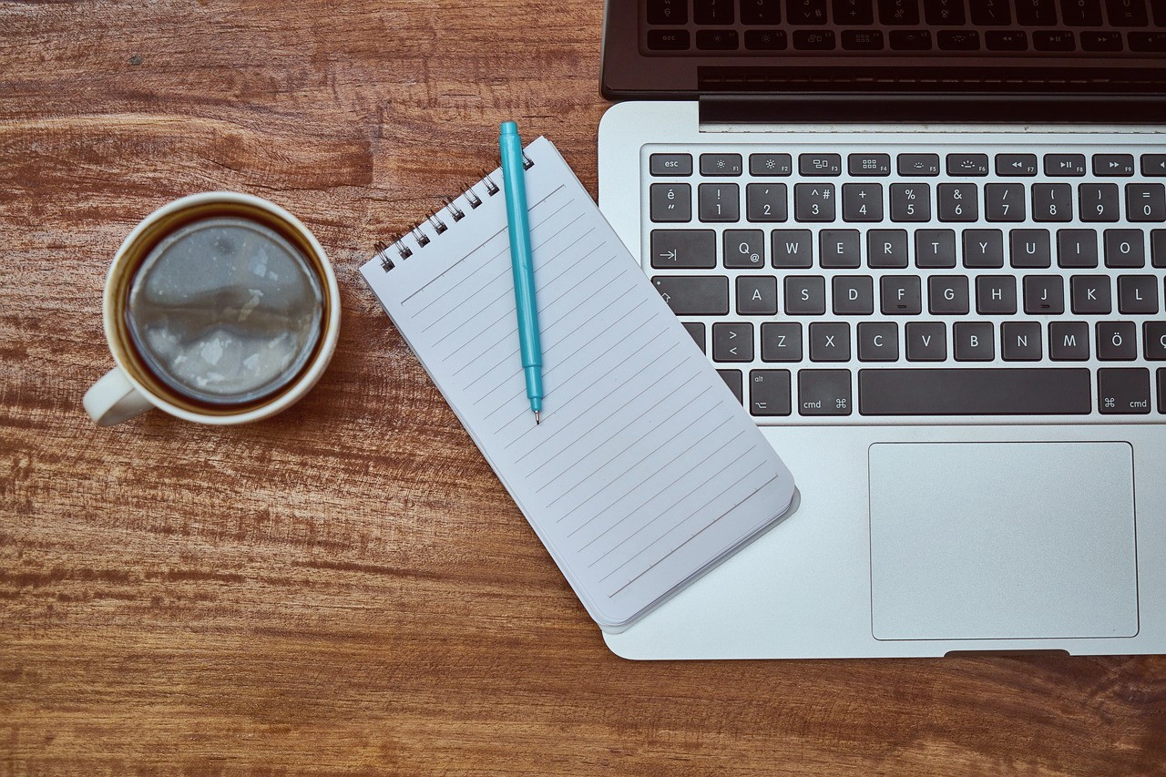 Calendario editoriale, cellulare, margherite e scotch su una scrivania bianca